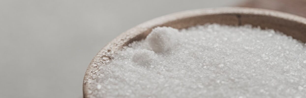 a wooden bowl of granulated sugar alternative sits on the edge of a table