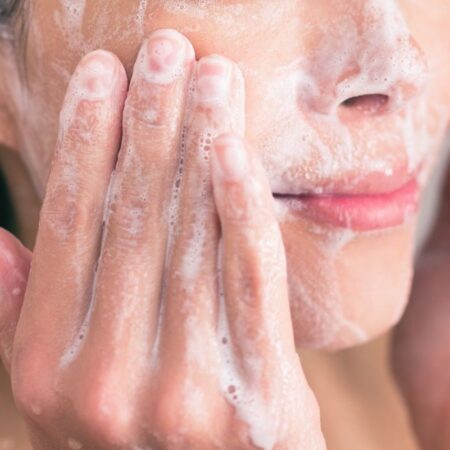 close up of woman washing face with personal care face wash