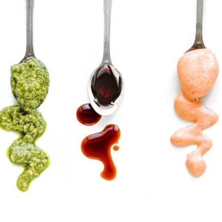 three spoons drizzling sauce and condiments used in food products