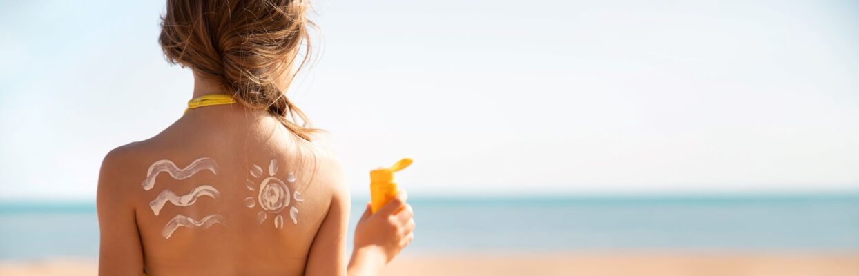 woman facing ocean with sunscreen on her shoulders