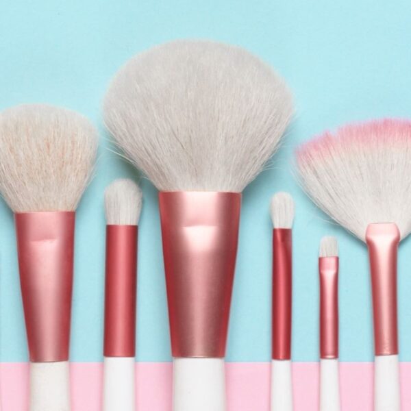 multicolored makeup brushes arranged on blue background
